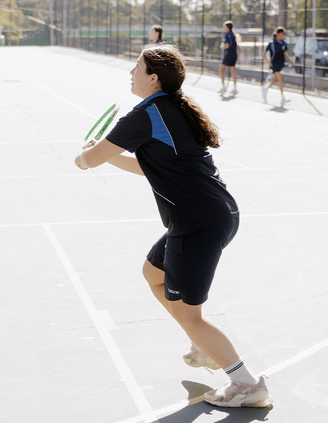 Student playing tennis on Cerdon College Merrylands netball court