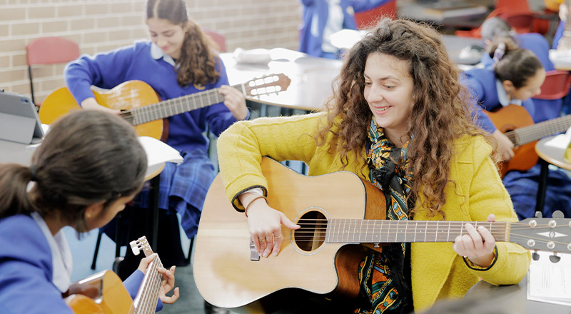 Cerdon Catholic College Merrylands teacher holds guitar in music classroom