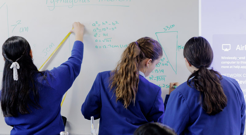 Students writing on whiteboard at Cerdon College Merrylands